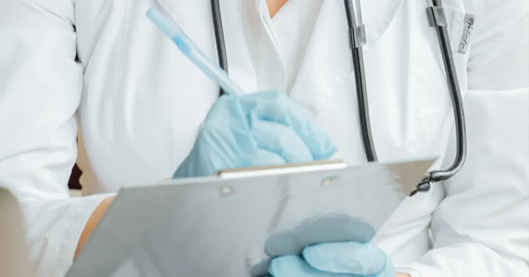 Person in PPE writes on clipboard