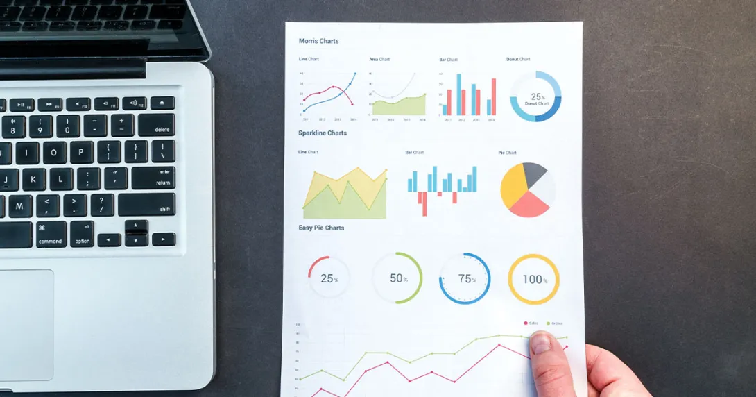 A section of a laptop appears next to print outs of health research data analytics.