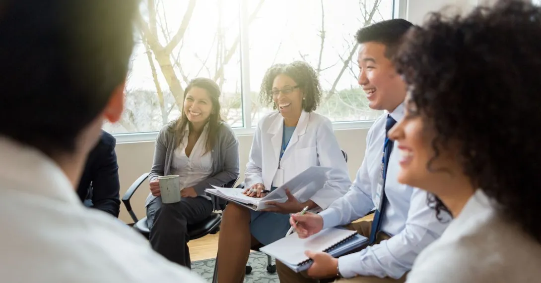 Smiling health system colleagues sit together and talk