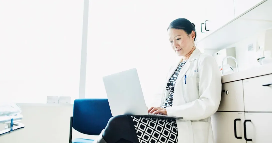 A doctor checking on a patients file on a laptop computer