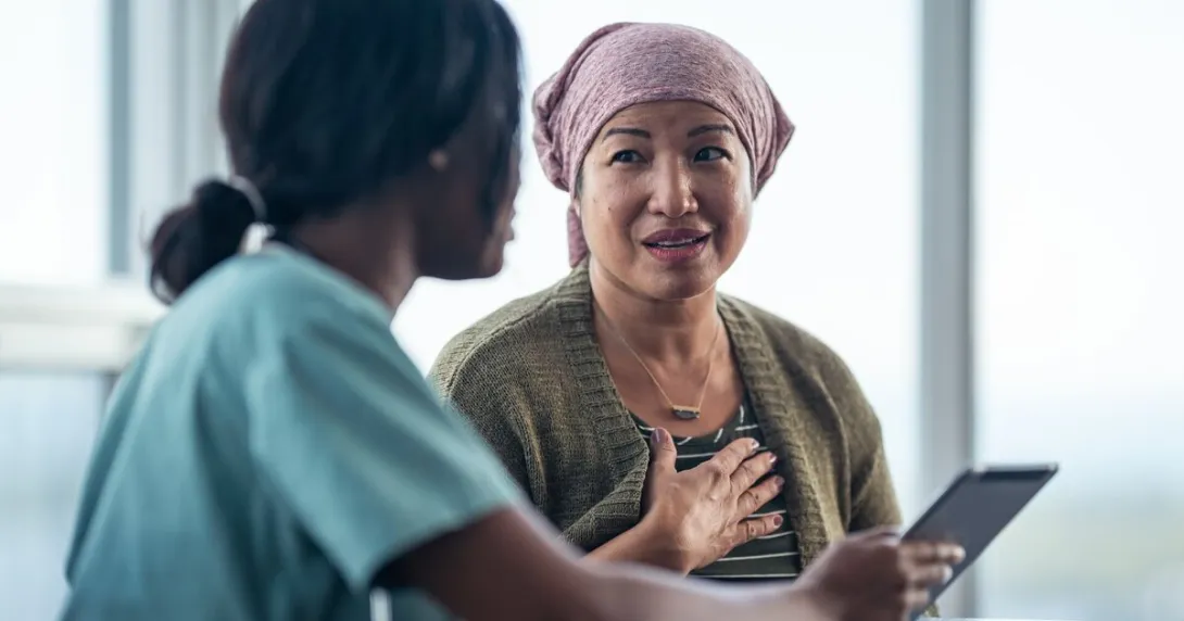 A nurse discussing a cancer patient's treatment plan using a digital tablet