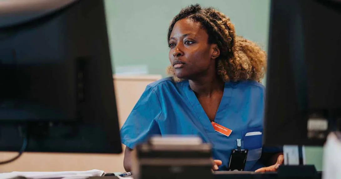 Healthcare worker using a computer with dual monitors