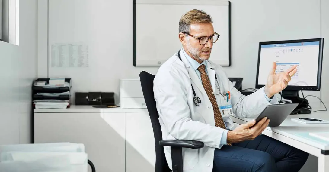 Doctor at desk talking to tablet
