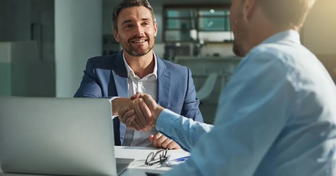 Practice manager shakes hands with a vendor across a desk 