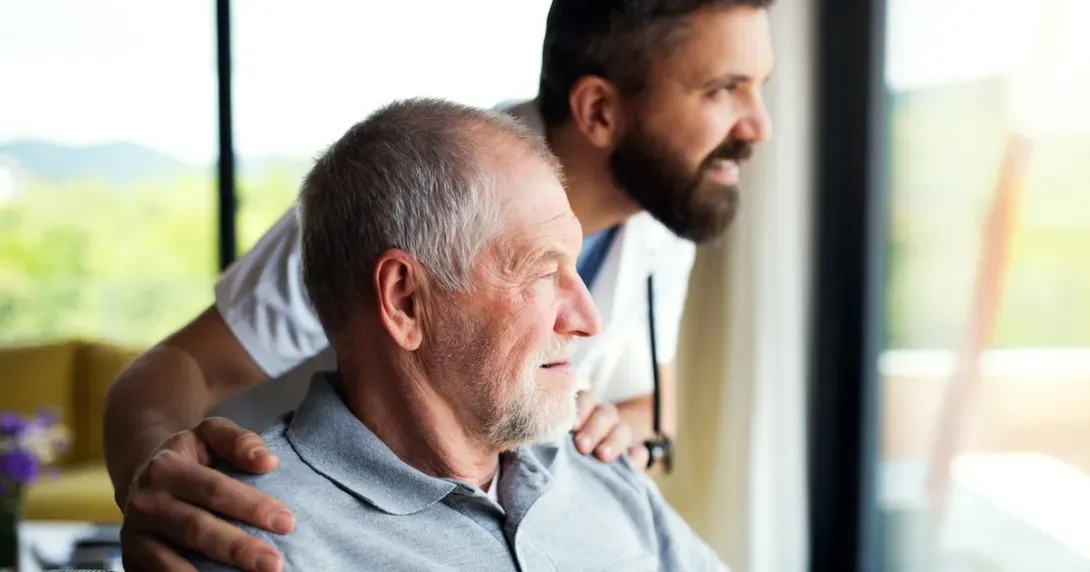 Medicare patient and caregiver look out a window and smile