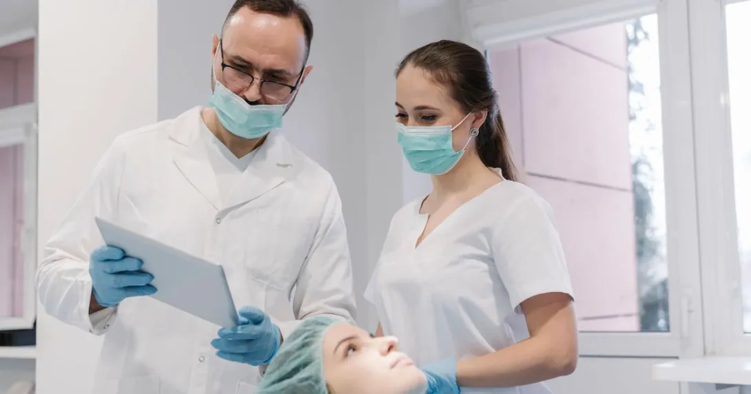 A dentist and an assistant are preparing for a dental procedure