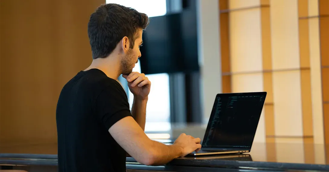 Health IT developer works on his laptop at a table