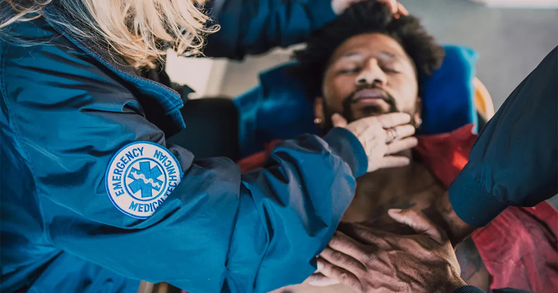 A man lays on a stretcher and receives care from EMTs 