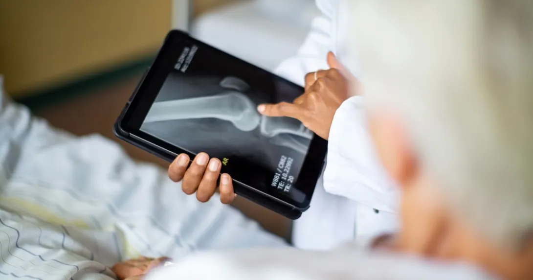 A doctor showing a bone X-ray on a digital tablet to a patient 
