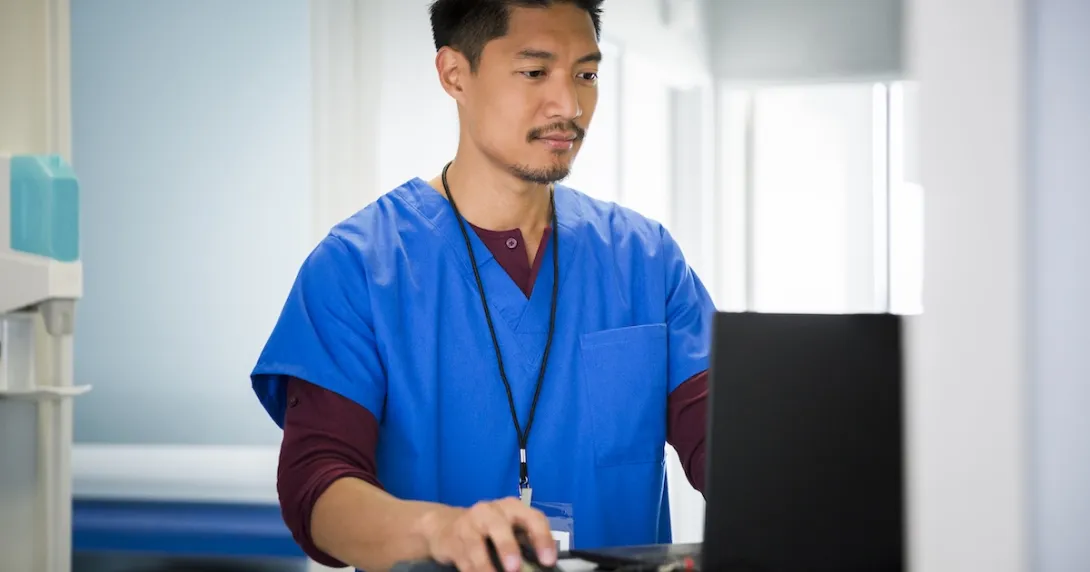 A nurse accessing a patient's record on a laptop computer