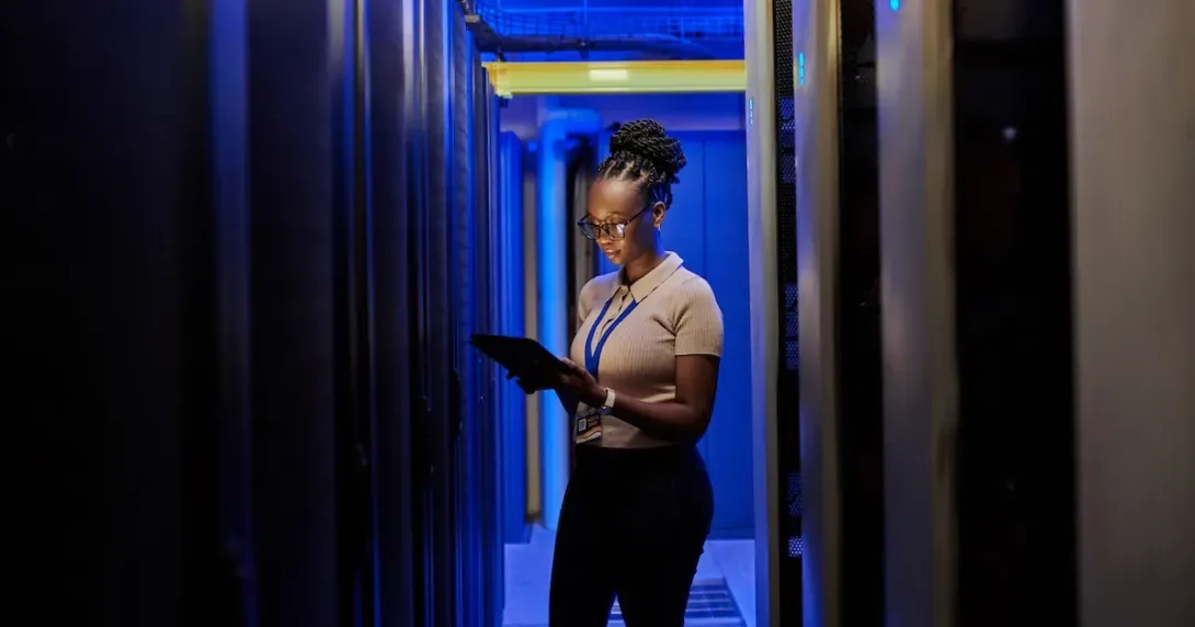 Woman reviews information on a laptop in a server room
