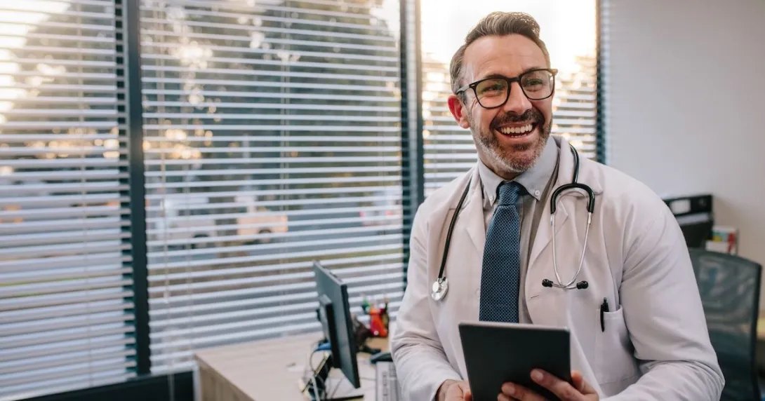 A smiling doctor at a clinic holding a digital tablet