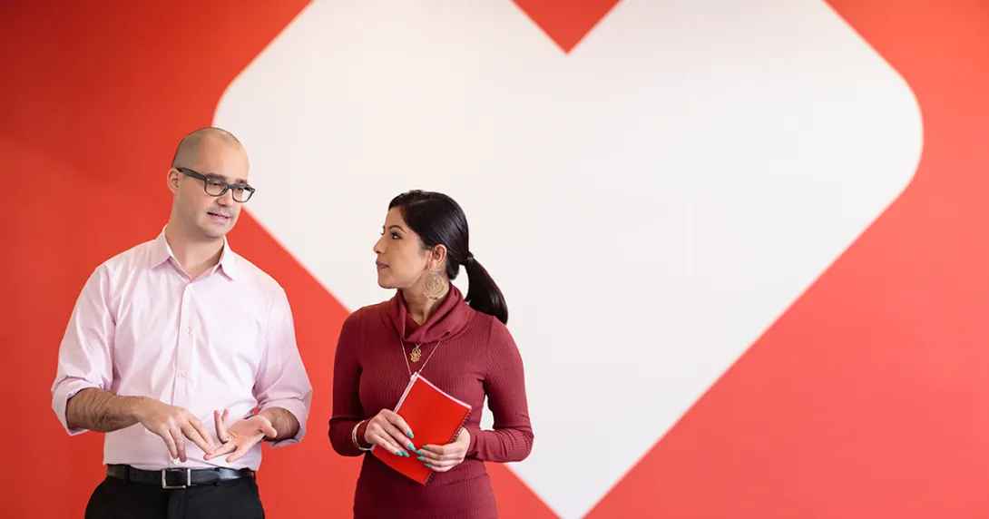 A man and a woman appear talking in front of the CVS Health logo.