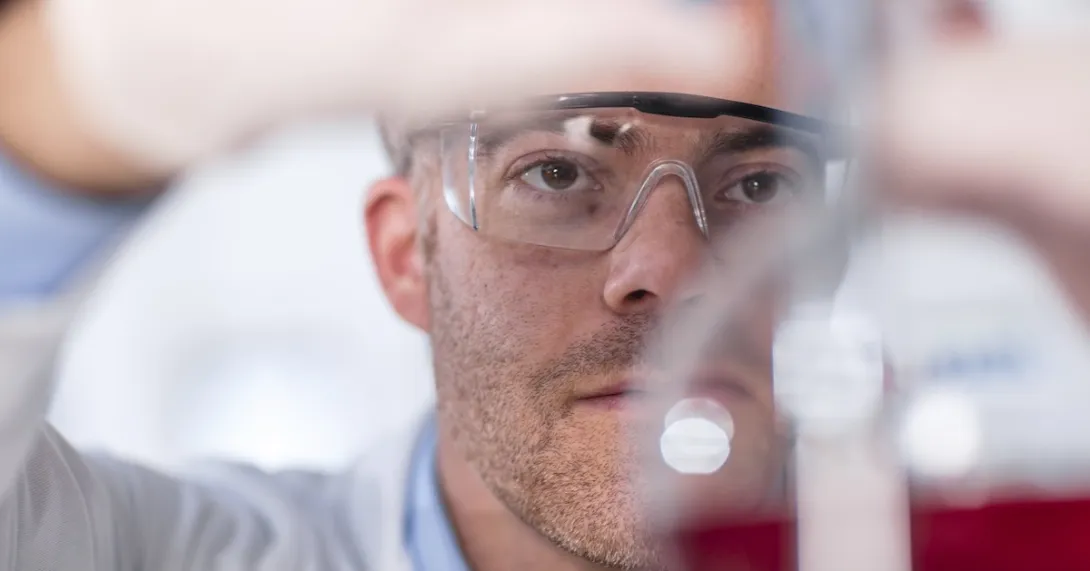 Lab worker looking at beaker