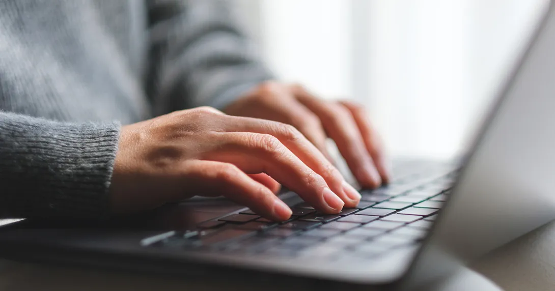 Hands typing on a laptop computer