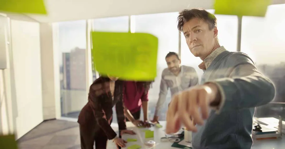 Co-workers reviewing ideas on glass wall_EMEA HITN_Getty-Shannon Fagan