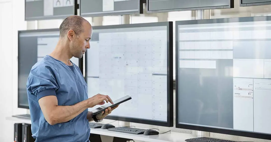 Healthcare worker with tablet looking at data displays