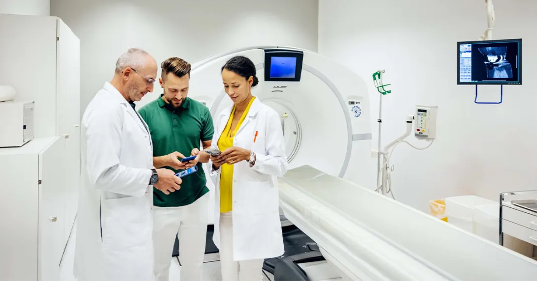 Healthcare workers looking at phones next to MRI machine