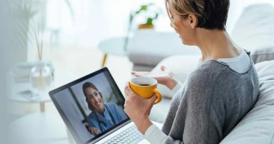 Person sitting on a couch with a laptop on their lap speaking with a healthcare professional virtually