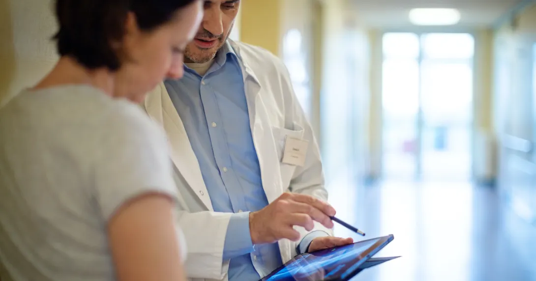 A radiologist showing a patient their x-ray report on a digital tablet