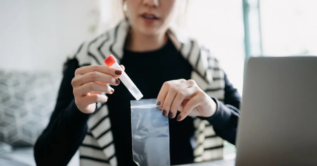 A person placing a medical test tube inside a plastic bag
