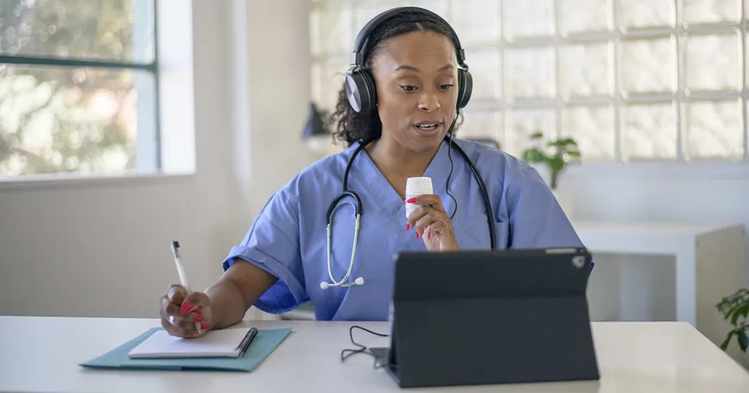 Doctor talking notes while talking to a tablet