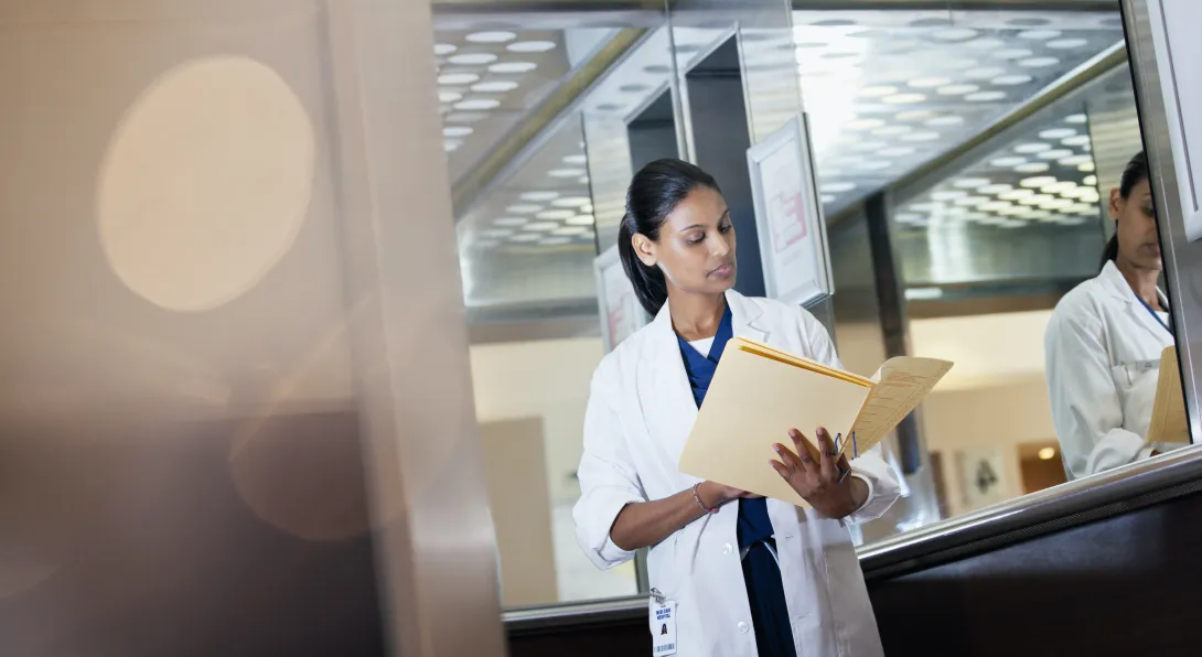 A doctor reading a paper health record from a folder