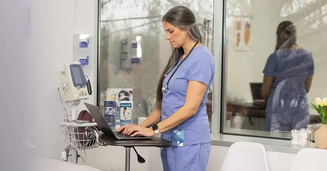 Healthcare worker using laptop in hospital room