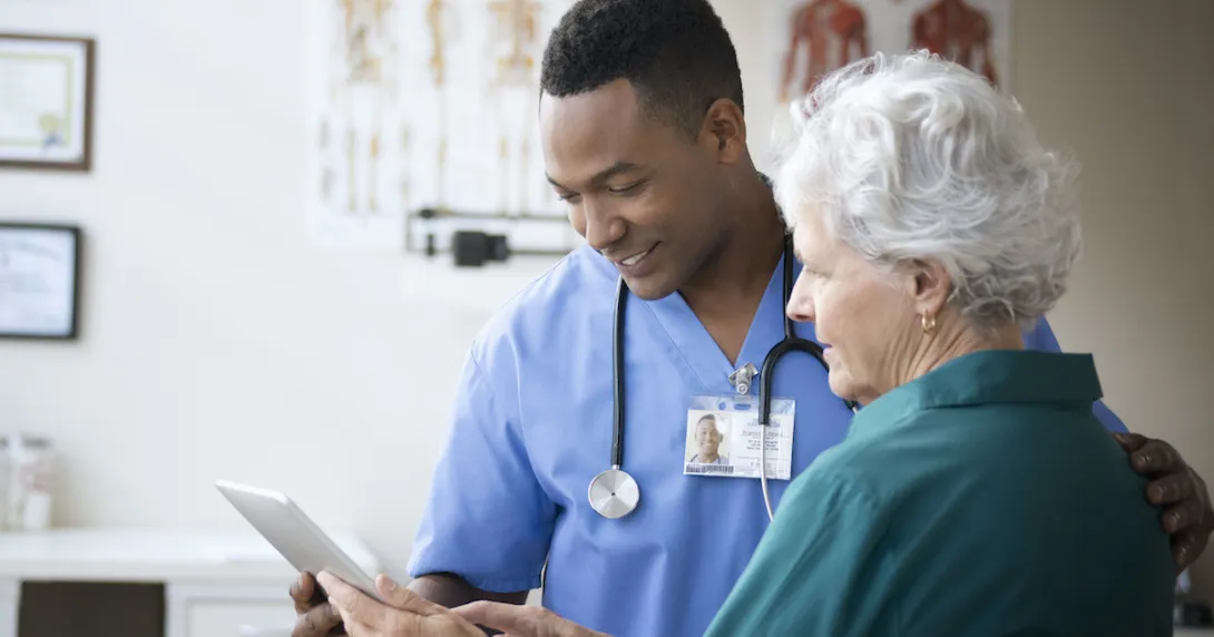 A nurse assisting an elderly in using a digital tablet