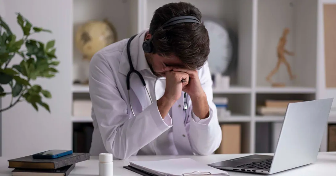 Doctor with head on hands and headset