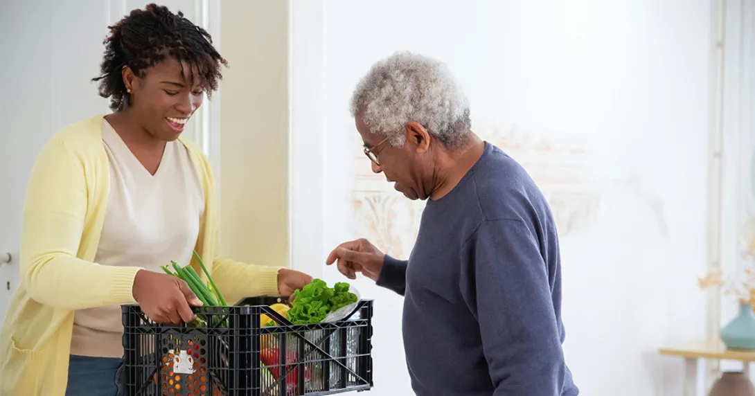 Woman holds a plastic delivery of prescription produce for an older man