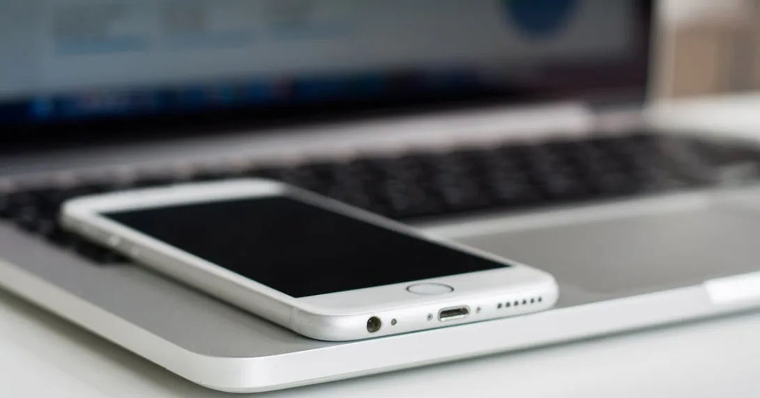 mobile phone lies on an open laptop