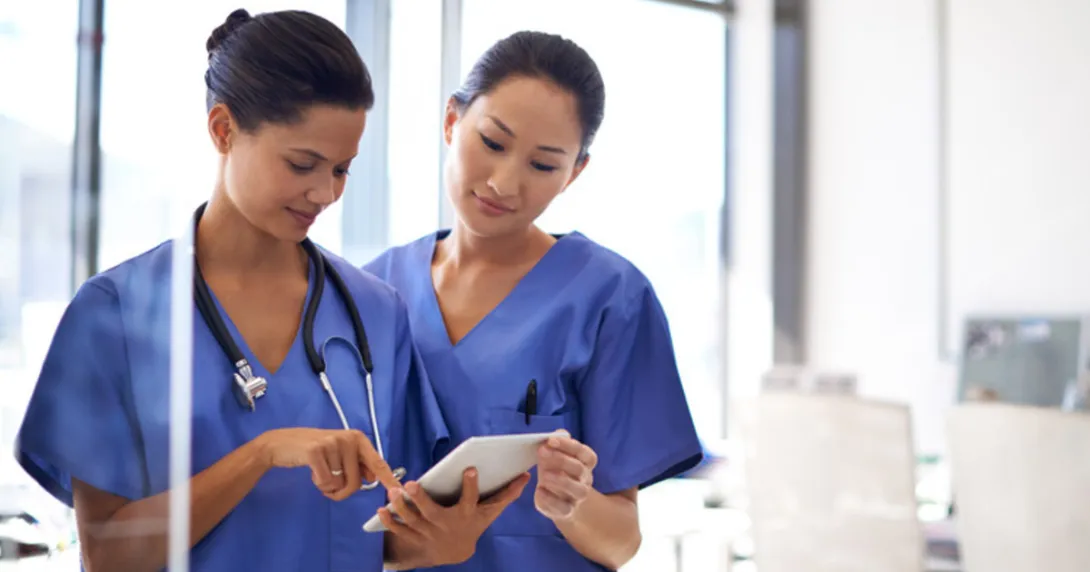 Two nurses check patient montitoring device