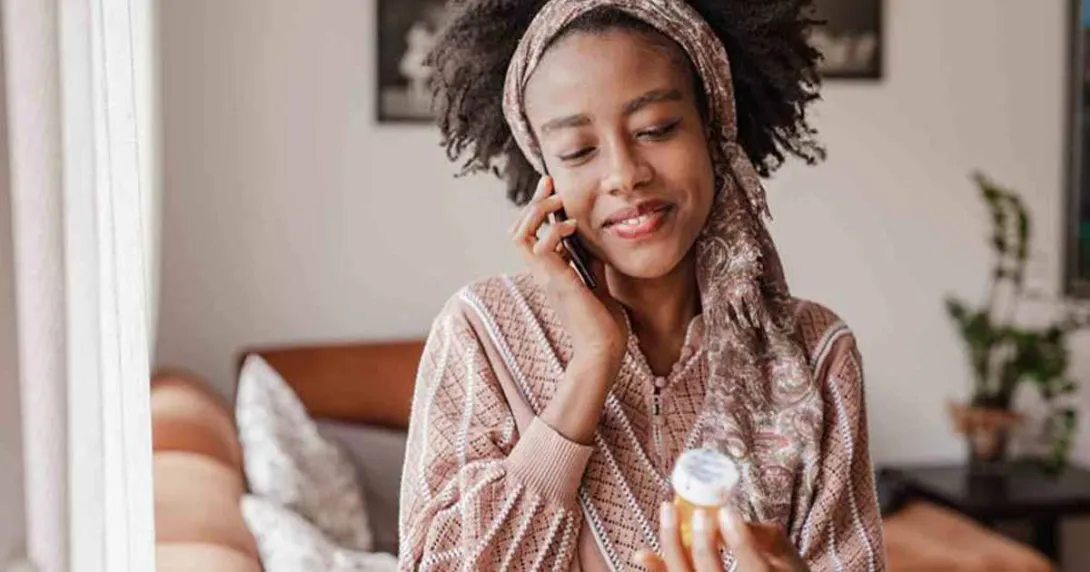 Person on the phone holding pill bottle