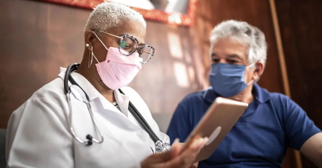 Doctor and patient in masks looking at a tablet