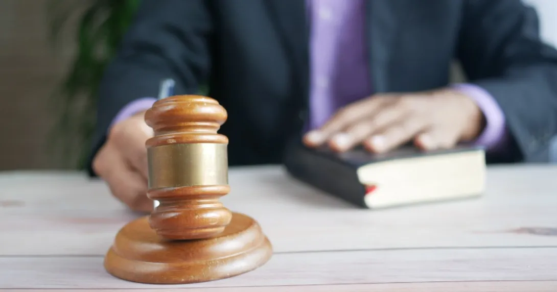 Man's hands show on bible and gavel at a table