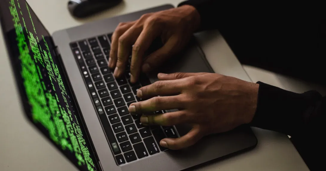 Hands on a laptop, and the screen shows code