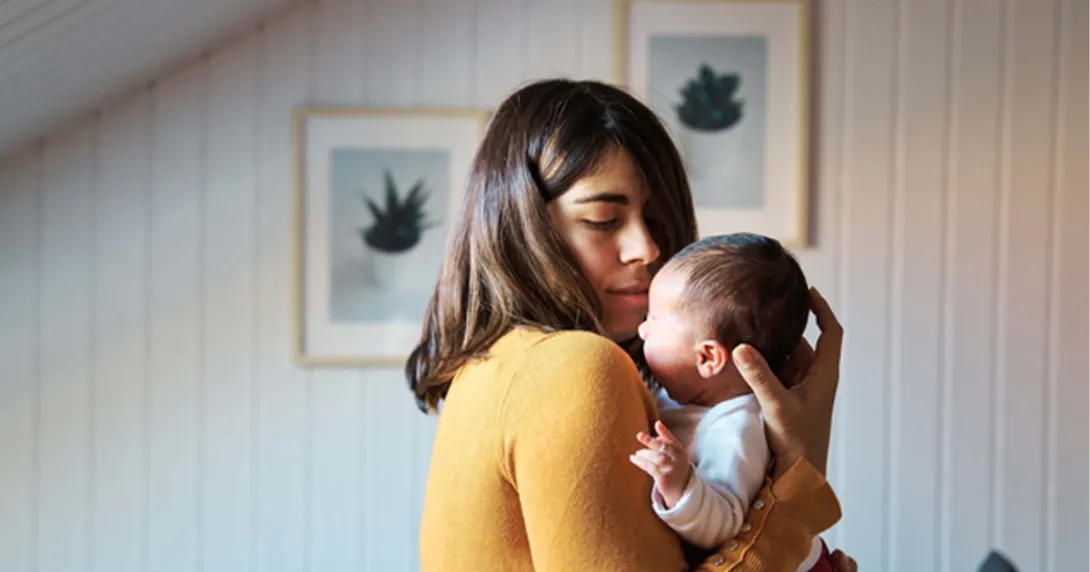 new mother in yellow holding infant