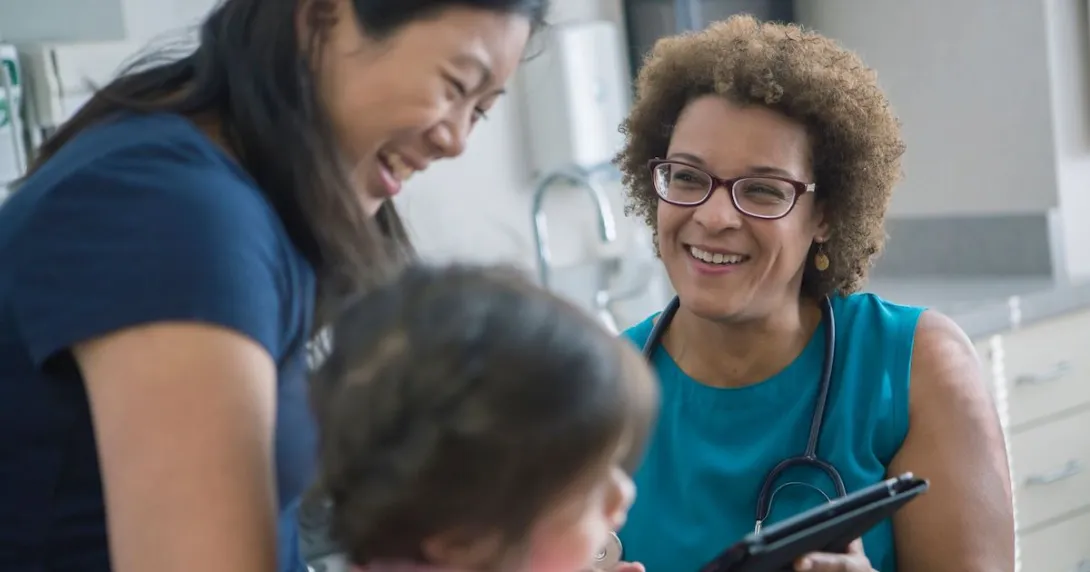 A female doctor laughs with a mother and daughter