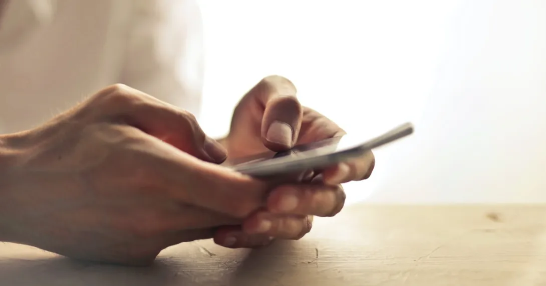 Hands on table holding a mobile phone