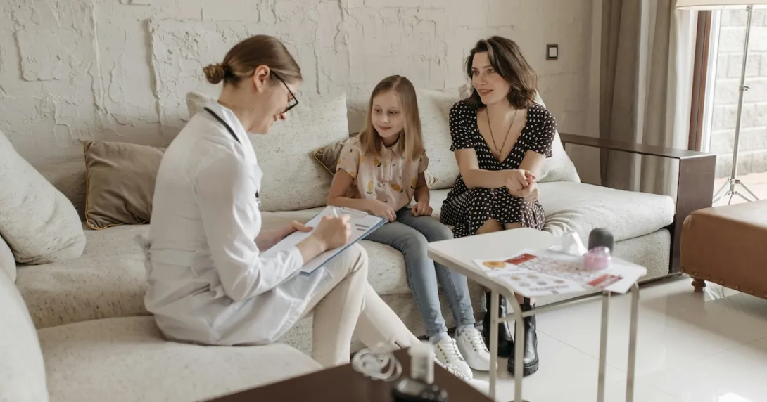 A parent and their kid in a consultation with a doctor