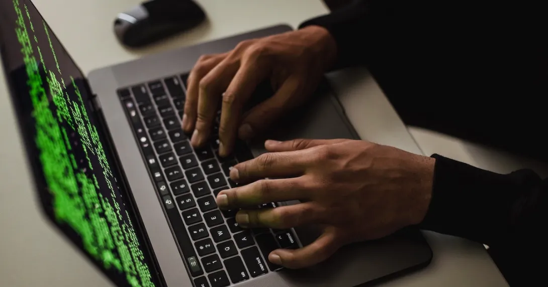 Hands typing on a laptop showing code only