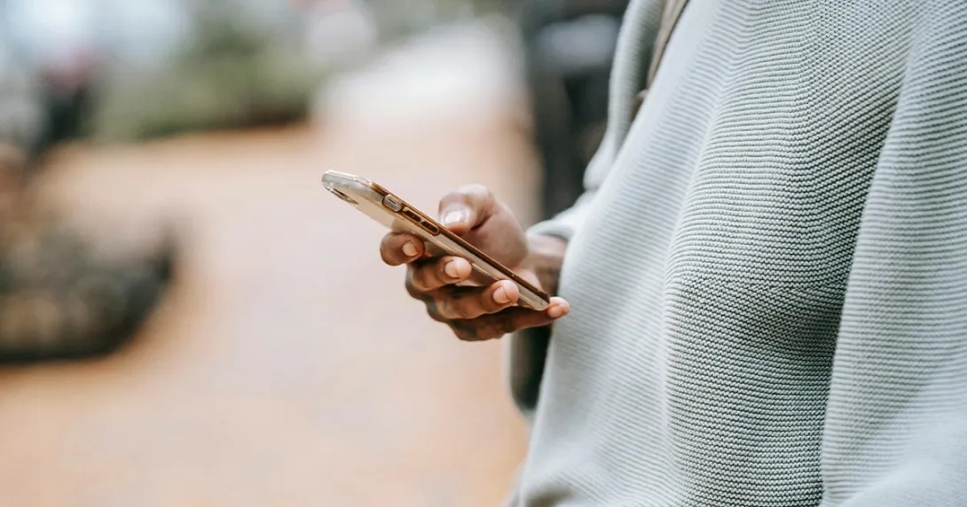 person in grey sweater using a mobile phone