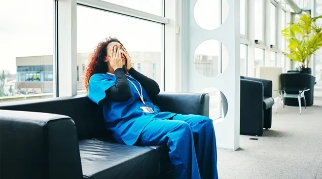 Healthcare worker in chair rubbing eyes