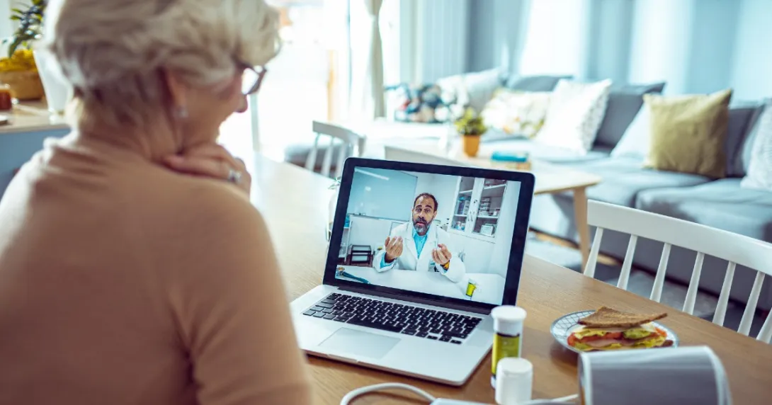 A person in home is having a telehealth appointment with a doctor via laptop.