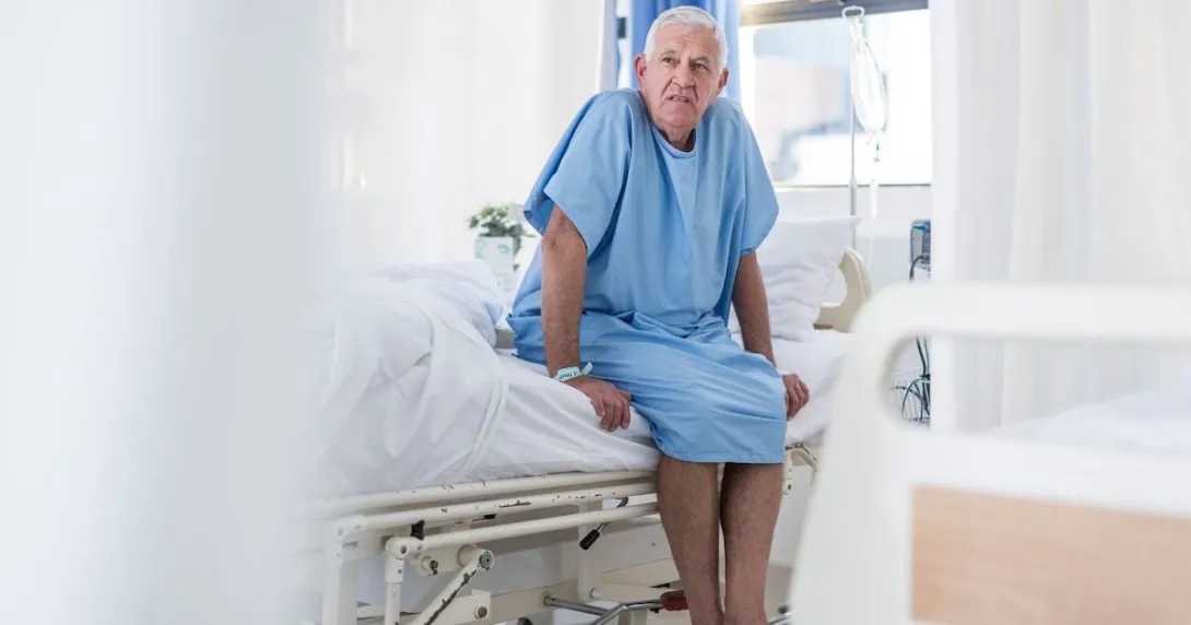 Patient sits in a patient gown in a medical exam room