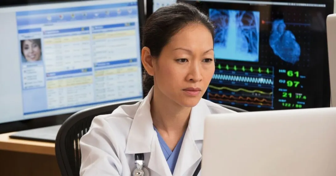 female doctor reviews patient data on multiple screens