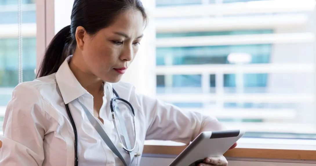 A doctor checking a patient's record on a digital tablet