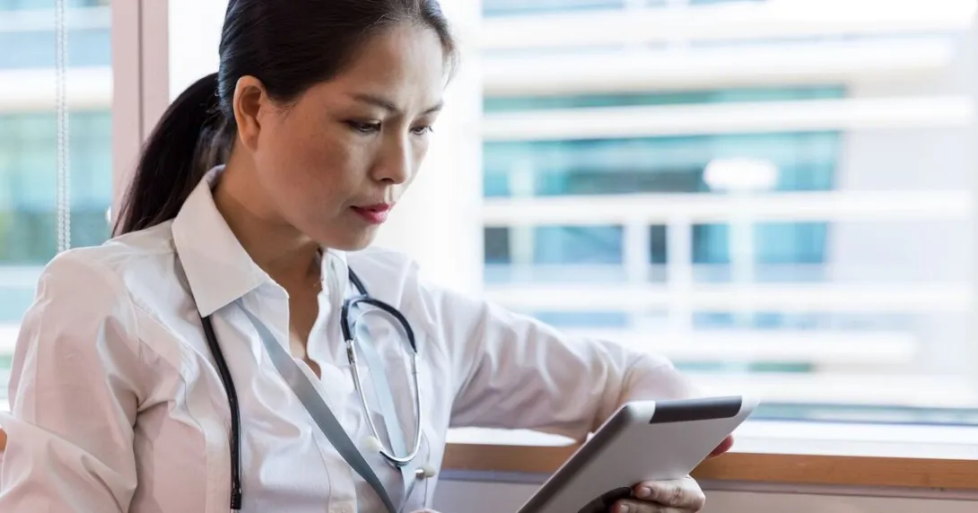 A doctor checking a patient's record on a digital tablet