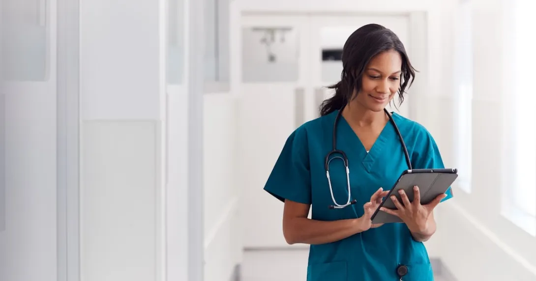 A doctor in scrubs reviewing a patient's record on a digital tablet
